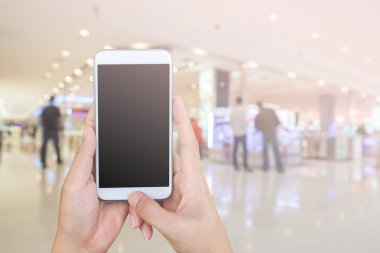Kadının ve akıllı telefon ile tutarak alışveriş merkezi backgrou bulanıklığı