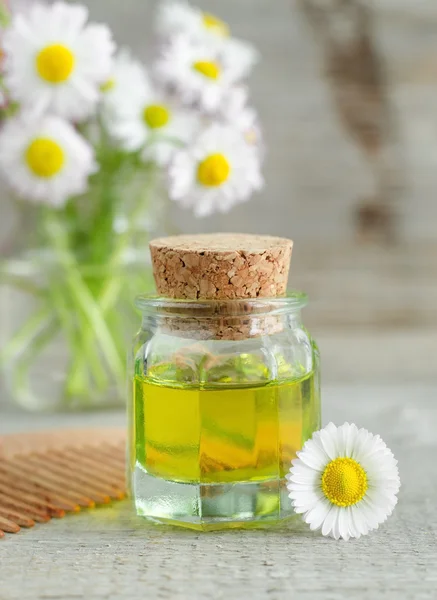 Pequeña botella de aceite de manzanilla cosmética y peine de madera —  Fotos de Stock