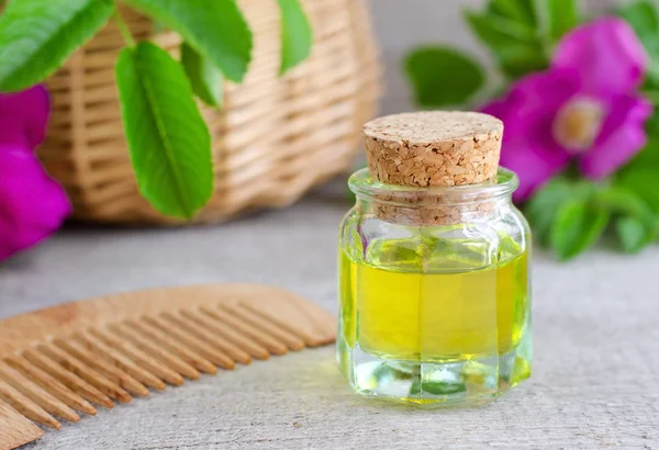 Small  bottle of natural cosmetic (massage) oil and wooden hair comb — Stock Photo, Image