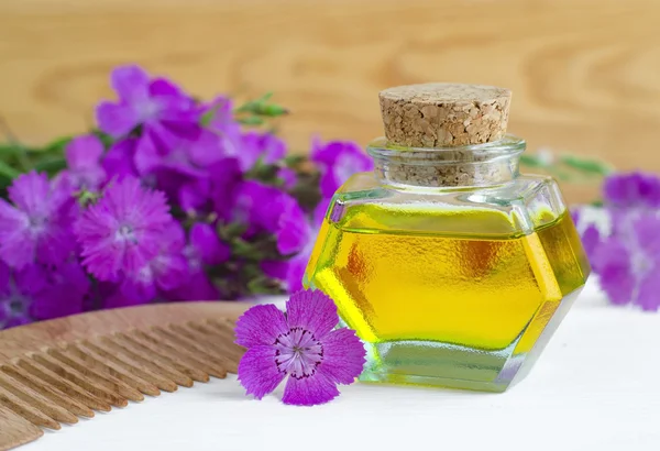 Pequeña botella de aceite cosmético natural y peine de madera — Foto de Stock