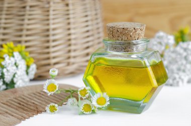 Small bottle of cosmetic oil with flowers and herbal extracts and wooden hair comb for natural hair care clipart