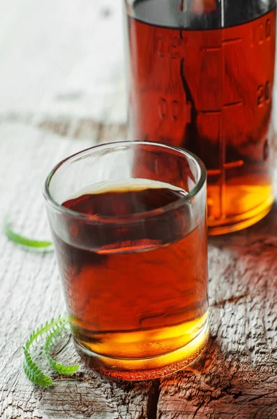 Маленький стакан алкогольного напитка или медицинская настойка на деревянном фоне — стоковое фото
