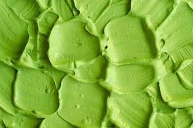 Yeşil kozmetik kil (salatalık yüz maskesi, avokado yüz kremi, yeşil çay eşleşmesi vücut ambalajı) yakından seçici odaklanma. Fırça darbeleriyle soyut arkaplan. 