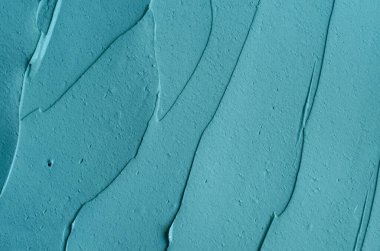 Turkuaz kozmetik kil (yosun maskesi, yüz kremi, spirulina vücut ambalajı) dokusu yakın, seçici odaklanma. Fırça darbeleriyle soyut arkaplan.