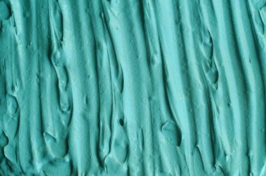 Turkuaz kozmetik kil (yosun maskesi, yüz kremi, spirulina vücut ambalajı) dokusu yakın, seçici odaklanma. Fırça darbeleriyle soyut arkaplan.