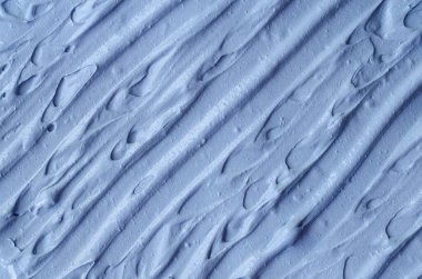 Açık mavi bentonit yüz kilini (aljinat maskesi, yüz kremi, vücut sargısı) kapat, seçici odaklanma. Fırça darbeleriyle soyut arkaplan. 