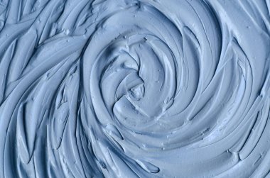 Açık mavi bentonit yüz kilini (aljinat maskesi, yüz kremi, vücut sargısı) kapat, seçici odaklanma. Çember fırça darbeleriyle soyut arkaplan. 