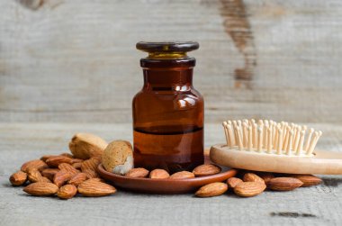 Badem yağı ve ahşap saç fırçalı eczane şişesi. Doğal saç bakım konsepti. Eski ahşap arka plan. Badem kapanıyor. Boşluğu kopyala