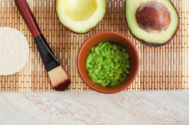 Küçük bir kasede taze avokado püresi ve makyaj fırçası. Ev yapımı yüz maskesi, doğal güzellik tedavisi ve spa tarifi. Üst görünüm, alanı kopyala. 