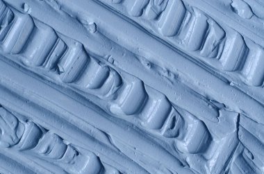 Açık mavi bentonit yüz kilini (aljinat maskesi, yüz kremi, vücut sargısı) kapat, seçici odaklanma. Fırça darbeleriyle soyut arkaplan. 