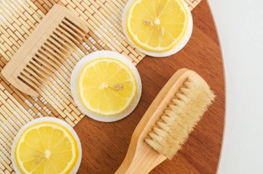 Limon dilimleri, pamuk pedler ve ahşap saç fırçaları. Ev yapımı saç maskesi ya da yüz toneri hazırlamak için gerekli malzemeler. Doğal güzellik tedavi tarifi ve sıfır atık konsepti. Üst görünüm, alanı kopyala. 