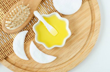 Kozmetik kaplı küçük beyaz kase (masaj, temizlik) yağ ve ahşap saç fırçası. Doğal saç bakımı, spa ve güzellik tedavi tarifi. Üst görünüm, alanı kopyala. 