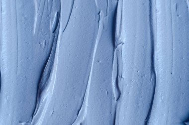 Açık mavi bentonit yüz kilini (aljinat maskesi, yüz kremi, vücut sargısı) kapat, seçici odaklanma. Fırça darbeleriyle soyut arkaplan. 