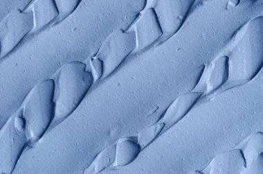 Açık mavi bentonit yüz kilini (aljinat maskesi, yüz kremi, vücut sargısı) kapat, seçici odaklanma. Fırça darbeleriyle soyut arkaplan. 