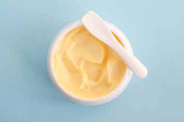 Sarı yüz maskesi (muz yüz kremi, saç maskesi, vücut yağı). Doğal cilt ve saç bakımı konsepti. Açık mavi arkaplan. Üst görünüm, alanı kopyala.