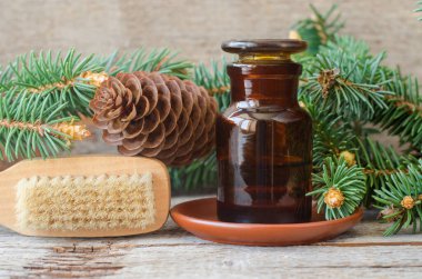 Temel köknar yağı (özüt, tentür, infüzyon) ve masaj fırçası içeren eczacı şişesi. Eski ahşap arka plan. Aromaterapi, sauna, spa ve bitkisel ilaç konsepti. Boşluğu kopyala. 