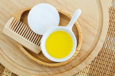 Kozmetik aroma yağı, pamuk ped ve ahşap saç fırçasıyla küçük beyaz bir kase. Doğal cilt bakımı, ev yapımı spa ve güzellik tedavi tarifi. Üst görünüm, alanı kopyala. 