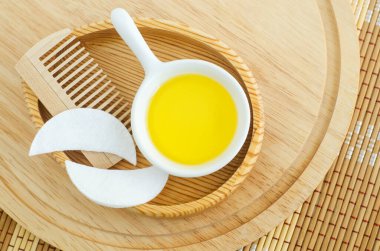 Kozmetik yağı, pamuk göz bandı ve ahşap saç fırçası olan küçük beyaz bir kase. Doğal cilt bakımı, ev yapımı spa ve güzellik tedavi tarifi. Üst görünüm, alanı kopyala. 