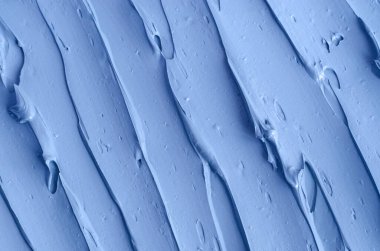 Açık mavi bentonit yüz kilini (aljinat maskesi, yüz kremi, vücut sargısı) kapat, seçici odaklanma. Fırça darbeleriyle soyut arkaplan. 