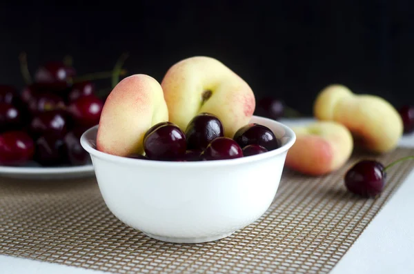 Ceri manis dan buah persik donat dalam mangkuk porselen — Stok Foto