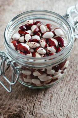 Red and white spotted beans in a glass jar clipart