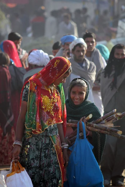 Indické dívky, chůze v Pushkar velbloudí veletrh drží vaky, prostřednictvím lidí — Stock fotografie