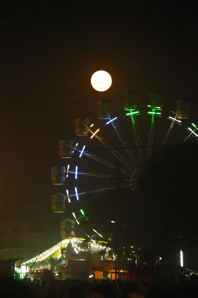 Ferris wheel illuminated in the dark sky with the full moon — Stock Photo, Image