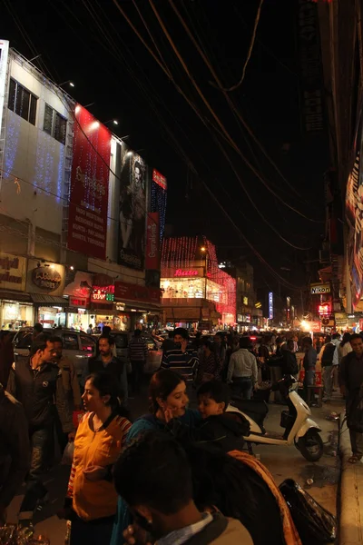 Nueva Delhi de noche. Vista nocturna de una calle comercial iluminada con gente caminando por todas partes — Foto de Stock