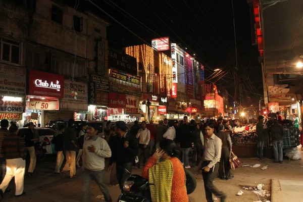 Νέο Δελχί, από τη νύχτα. Νυχτερινή άποψη της μια εμπορική οδό που φωτίζεται με τους ανθρώπους που περπατούν γύρω — Φωτογραφία Αρχείου