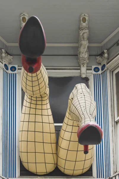 Velké nohy s síťované punčochy visící z okna — Stock fotografie