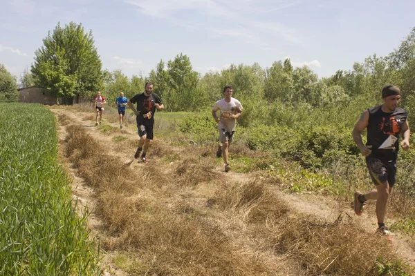 Skupina lidí běží venkovní v poli v Toskánsku — Stock fotografie