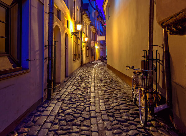Narrow street road between ancient building houses, night and street lamps illuminations