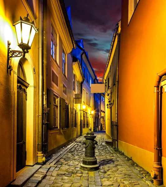 Narrow street, road between ancient and medieval building houses,  night and street lamps illuminations