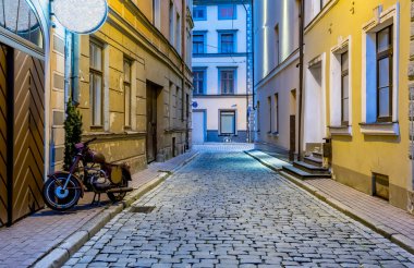 Eski binalar arasındaki dar yol, motosiklet park edilmiş.  