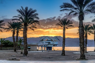 Avuç içi ve gezinti güvertesi ile renkli manzara ve Eilat 'ın merkez halk plajında gün doğumu - İsrail' in ünlü turistik beldesi ve eğlence şehri