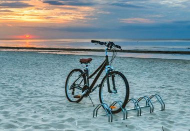 Gün batımında Baltık Denizi 'nin kumlu sahillerinde bisiklet sürmek