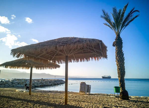 Morning on sandy beach in Eilat. Chairs and umbrella on the coastal line of the Red Sea
