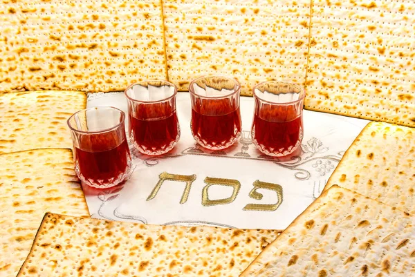 Pesah celebration concept - Jewish Passover holiday. Unleavened bread food  matzoh and drinking glass with red wine, selective focus on beverage, blurred vertical part of bread for copy space, Translation of Hebrew letters means Jewish Passover