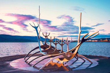 İzlanda 'nın başkenti Reykjavik' in limanında gün batımından sonra bulutlara karşı deniz kenarında bulunan ünlü heykel Sun Voyager 'ın (Viking gemisi) sembolü..