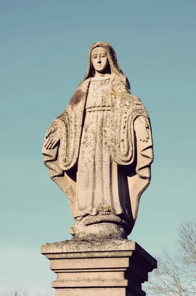 Old stone statue of the Virgin on the tombstone in the cemetery — Stock Photo, Image