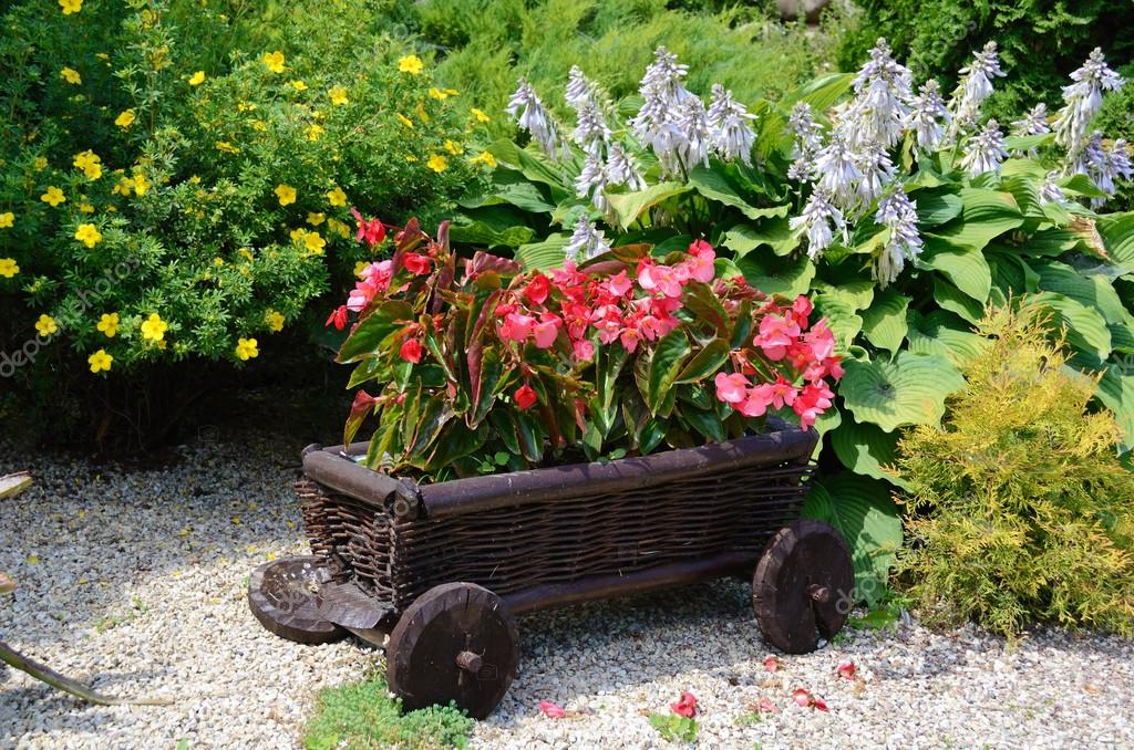 Red Flowers In The Garden On A Small Decorative Wooden Wagon Stock - Small Decorative Garden Wagon Red Flowers In The Garden On A Small Decorative Wooden Wagon Stock - Small Decorative Garden Wagon