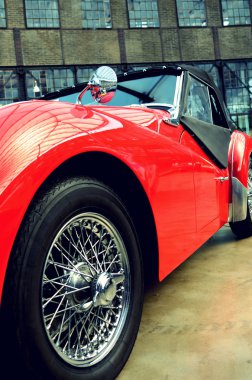 Stylish retro red car with a wheel with spokes and metallic mirr