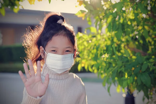 Dur işaretini gösteren tıbbi maske takan Asyalı kızın portresi. Yeni normal kavramları ve sosyal mesafeleri kabul et. Koronavirüsten korunmak için insanlar her evden çıkışlarında maske takarlar..
