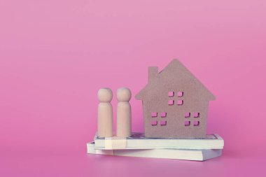 Bir çift oyuncak bebek odunu paraların üzerinde duruyor, pembe arka planda fotokopi alanı olan aşkları gösteriyorlar. Konsept işletme, finans, bankacılık, konut kredisi.