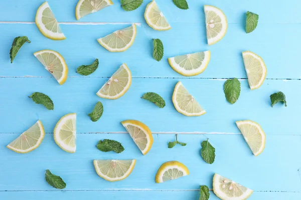 Group lemon cut slices with mints leaf freshness on blue wooden background. Concept background, flat lay, top view.