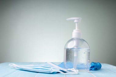 Şişe alkol jeli ve mavi eldivenli tıbbi maske. Şu anda, Coronavirus salgını hâlâ dünyada kol geziyor. Herkesin ellerini yıkaması, tıbbi maske takması gerekiyor..