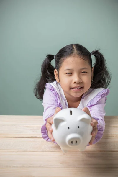 Financial, childhood, saving, planning education concept. Asian beautiful little cute kid girl holding the white piggy bank with copy space. Savings money for education to the future.