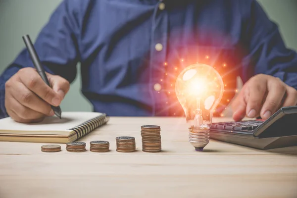 İşadamı, gelecekte yığınla para ile kredi yatırım işi için hesaplama ve kaydetme makineleri kullanır. Yenilik kavramlı yeni bir ampul fikri.