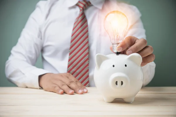 Zakenman Met Een Gloeilamp Met Witte Spaarpot Houten Tafel Het — Stockfoto