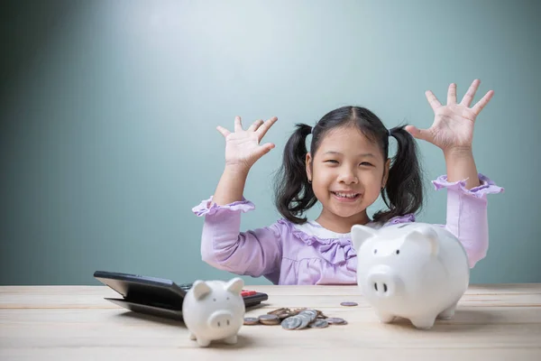 这位可爱的亚洲小女孩非常乐于存钱 将来可以和小猪银行 硬币和计算器一起生活 学习如何省钱和接受教育所必需的童年 — 图库照片